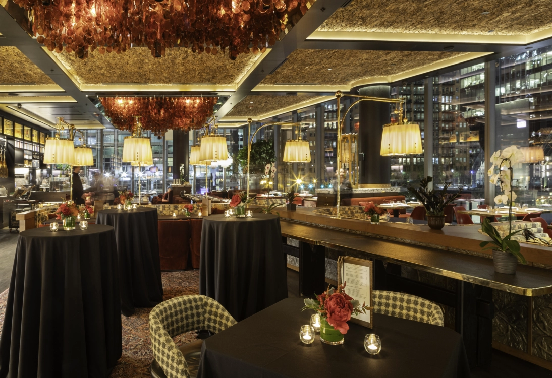 Elegant restaurant interior with floral centerpieces, checkered chairs, and warm lighting at night.