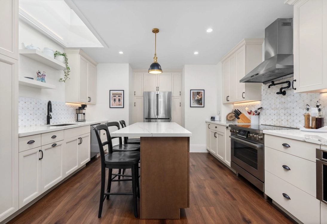 Modern kitchen interior featuring a central island, stainless steel appliances, and white cabinetry.