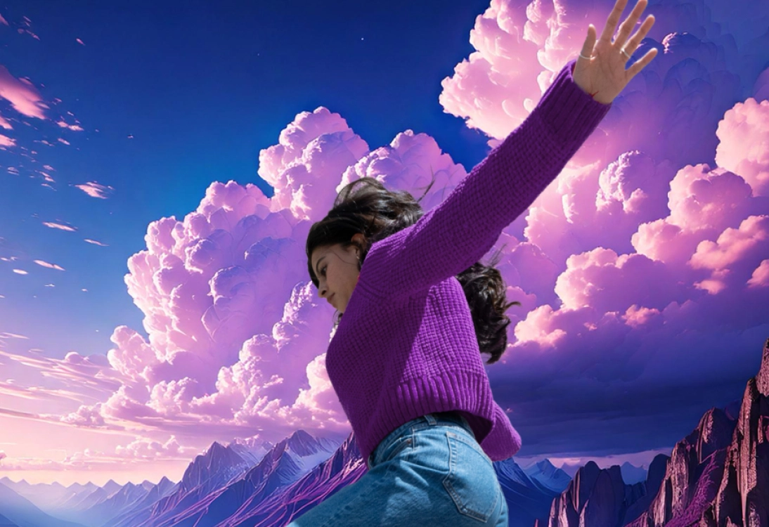 A figure in a purple sweater joyfully poses against a vibrant sky filled with dramatic clouds and mountains.
