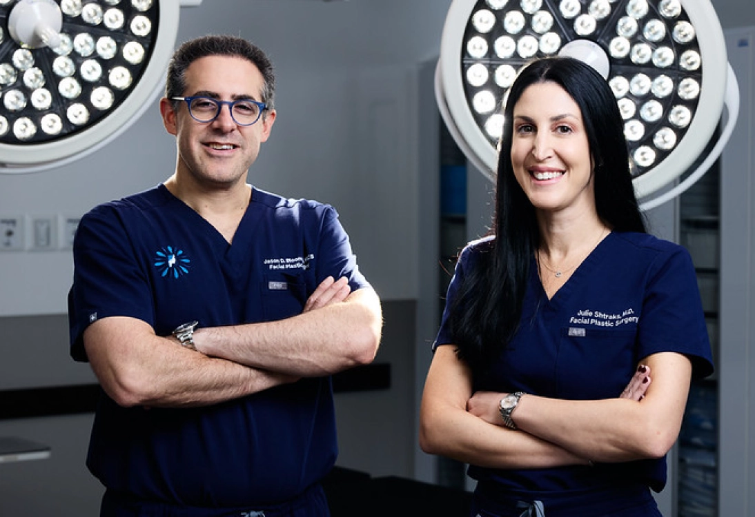 Two medical professionals in navy scrubs standing with arms crossed in an operating room.