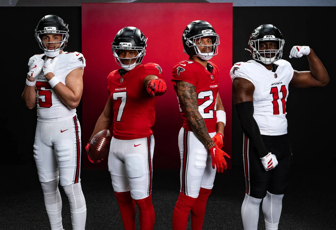 Four Atlanta Falcons football players in team uniforms posing on black background.