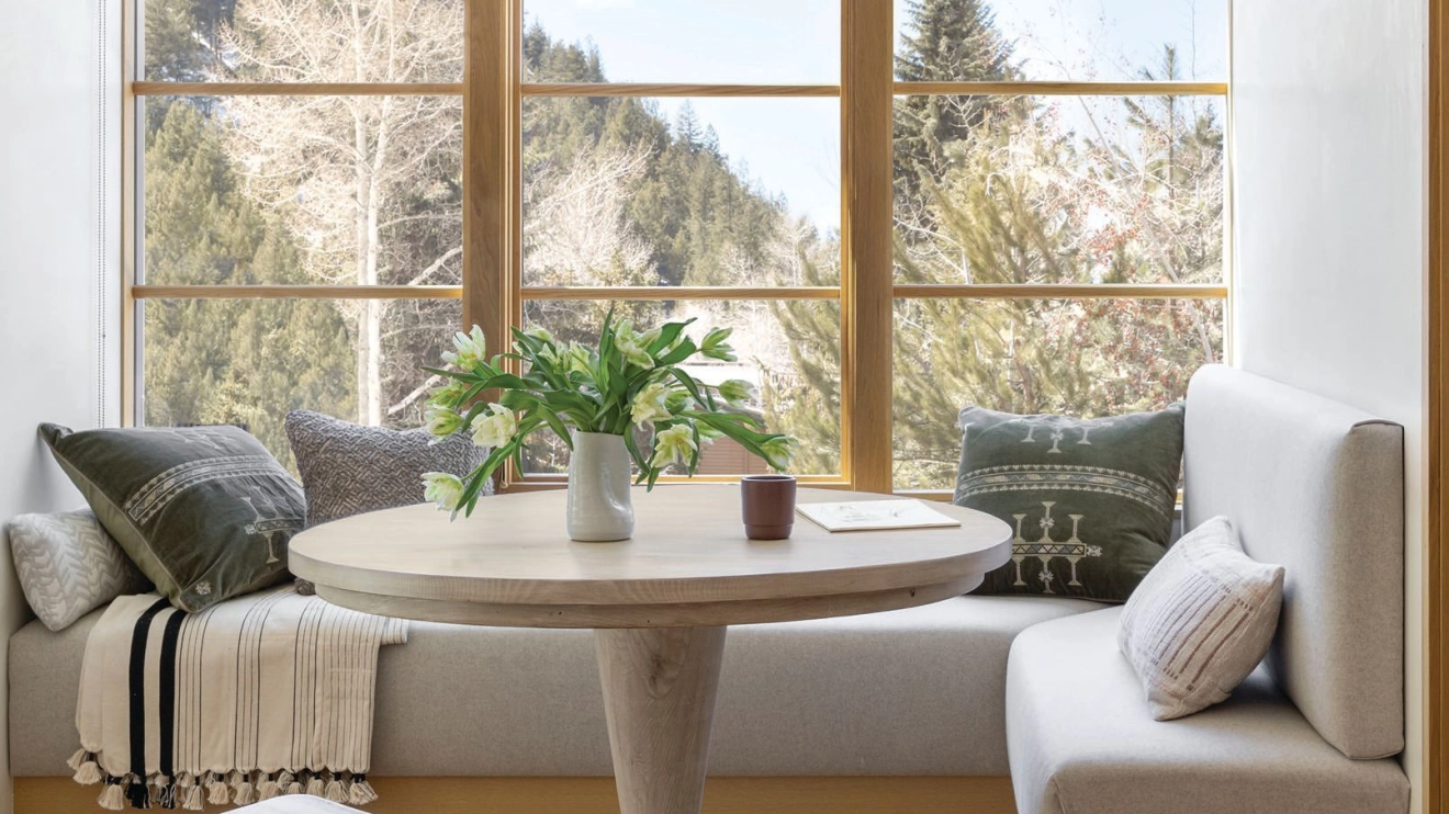 A cozy nook in the primary bedroom suite includes a Lulu and Georgia table and a banquette covered in Oatmeal double faced wool by Pollack. photographed by LISA ROMEREIN