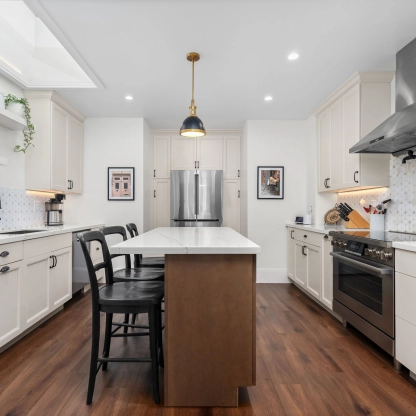 Modern kitchen interior featuring a central island, stainless steel appliances, and white cabinetry.