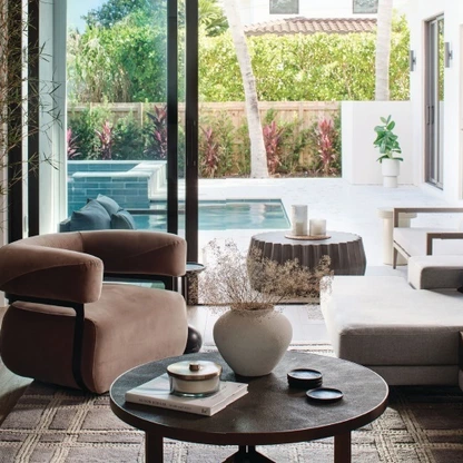 Modern living room with open sliding doors leading to a pool and outdoor seating area.