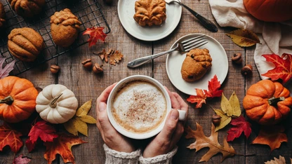 Top view of fall shaped pumpkin spice cakes and hands holding latte