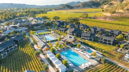 Aerial view of a resort with two swimming pools, surrounded by vineyards and hills.