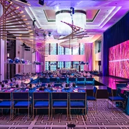 Modern banquet hall with purple lighting, geometric decorations, and long tables set for dining.