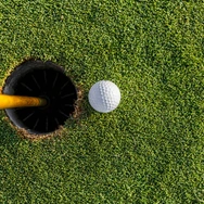 Golf ball near cup on green during sunny day at a golf course