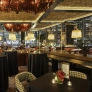 Elegant restaurant interior with floral centerpieces, checkered chairs, and warm lighting at night.