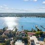 Aerial view of waterfront houses with private docks on a sunny day by a large body of water.