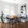 Bright dining nook with wooden table, clear chairs, bench seating, large abstract art, and cactus plant.