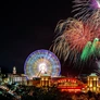 Nighttime fireworks display over Navy Pier with a lit Ferris wheel and illuminated buildings.