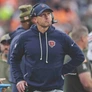 Coach wearing Chicago Bears hoodie and headset standing on football field during game.