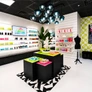 Bright, modern retail store interior with colorful products, geometric decor, black mannequins, and contemporary lighting fixtures.