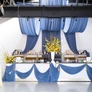 Event bar decorated with blue drapes, yellow floral arrangements, and elegant lighting fixtures.