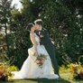 Bride and groom kissing outdoors during wedding ceremony with flower petals falling around them.