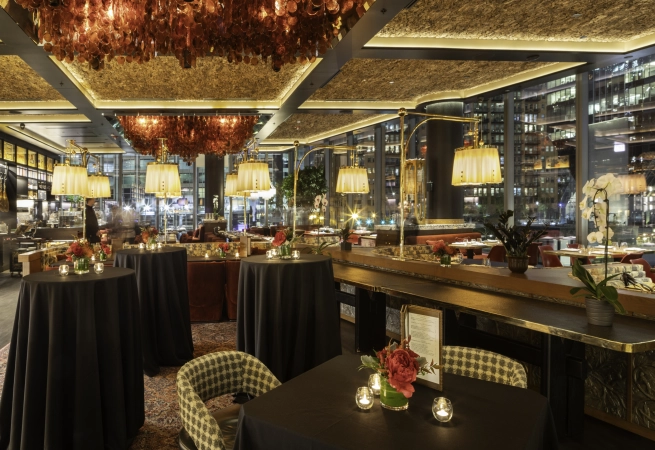 Elegant restaurant interior with floral centerpieces, checkered chairs, and warm lighting at night.