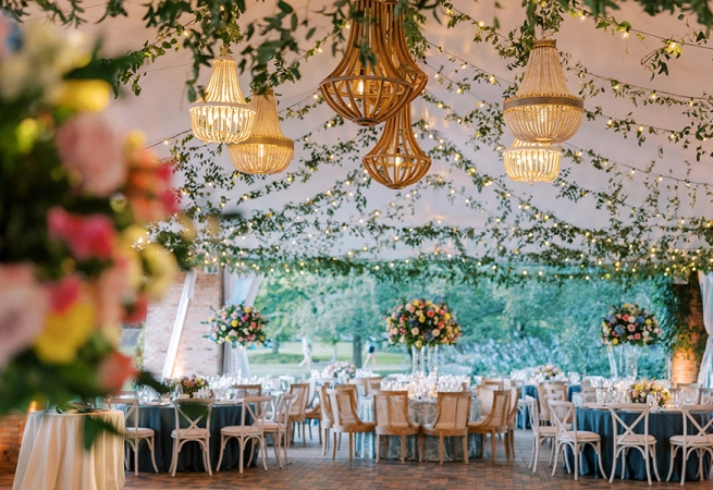 Elegant event space decorated with chandeliers, floral arrangements, and tables set for dining.