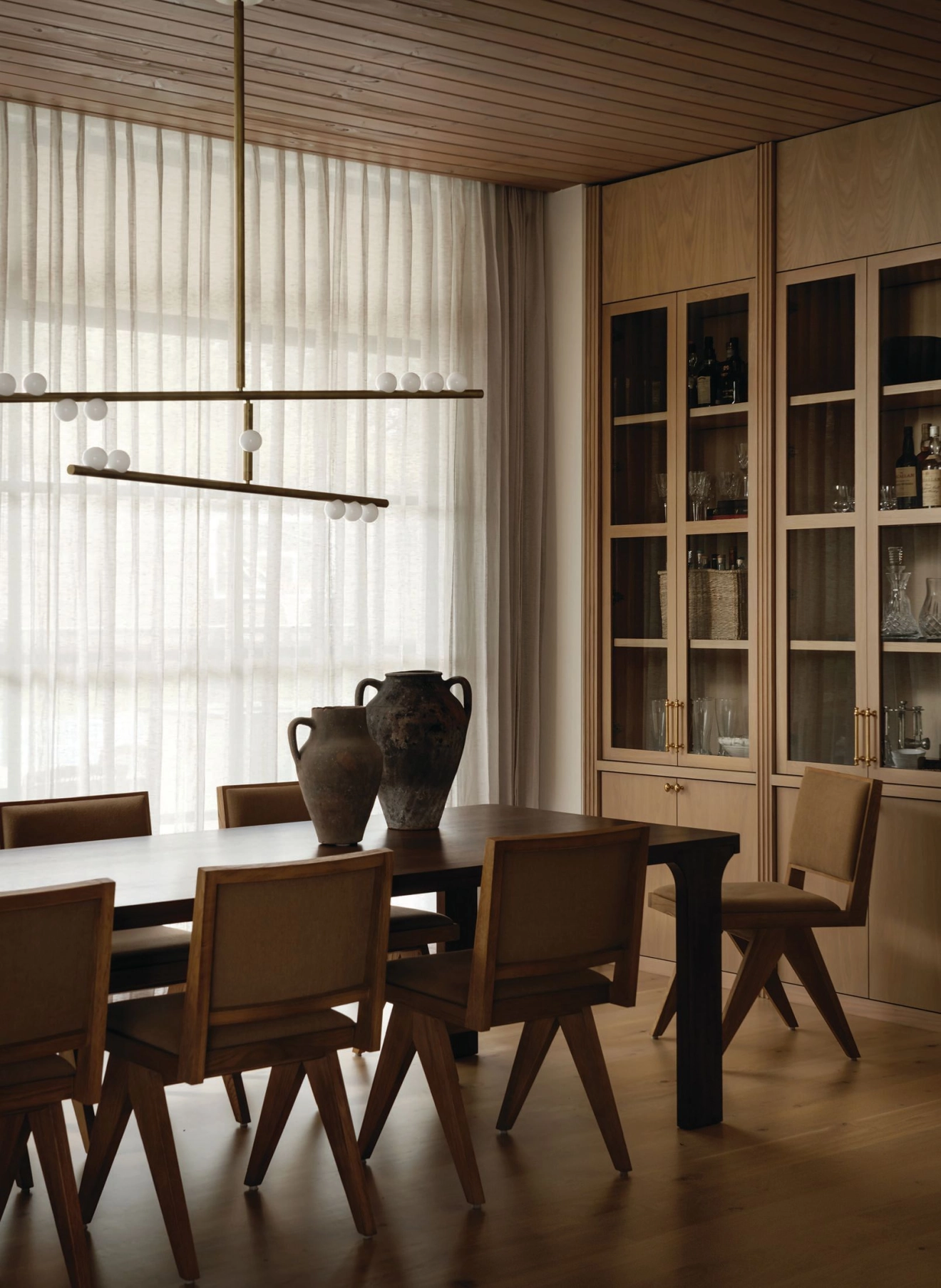 Diffused sunlight through sheer curtains and fluted glass cabinet fronts provide soft contrast to angular, modern Restoration Hardware furnishings and an abstract Lindsay Adelmann chandelier. Interiors photography by CHASE DANIELS