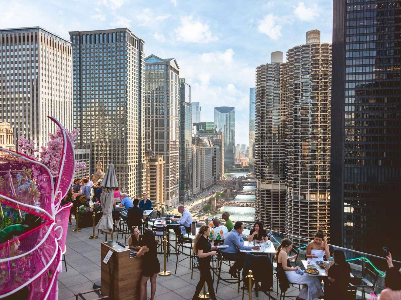 Rooftop restaurant with people dining, overlooking Chicago cityscape and Marina City towers.