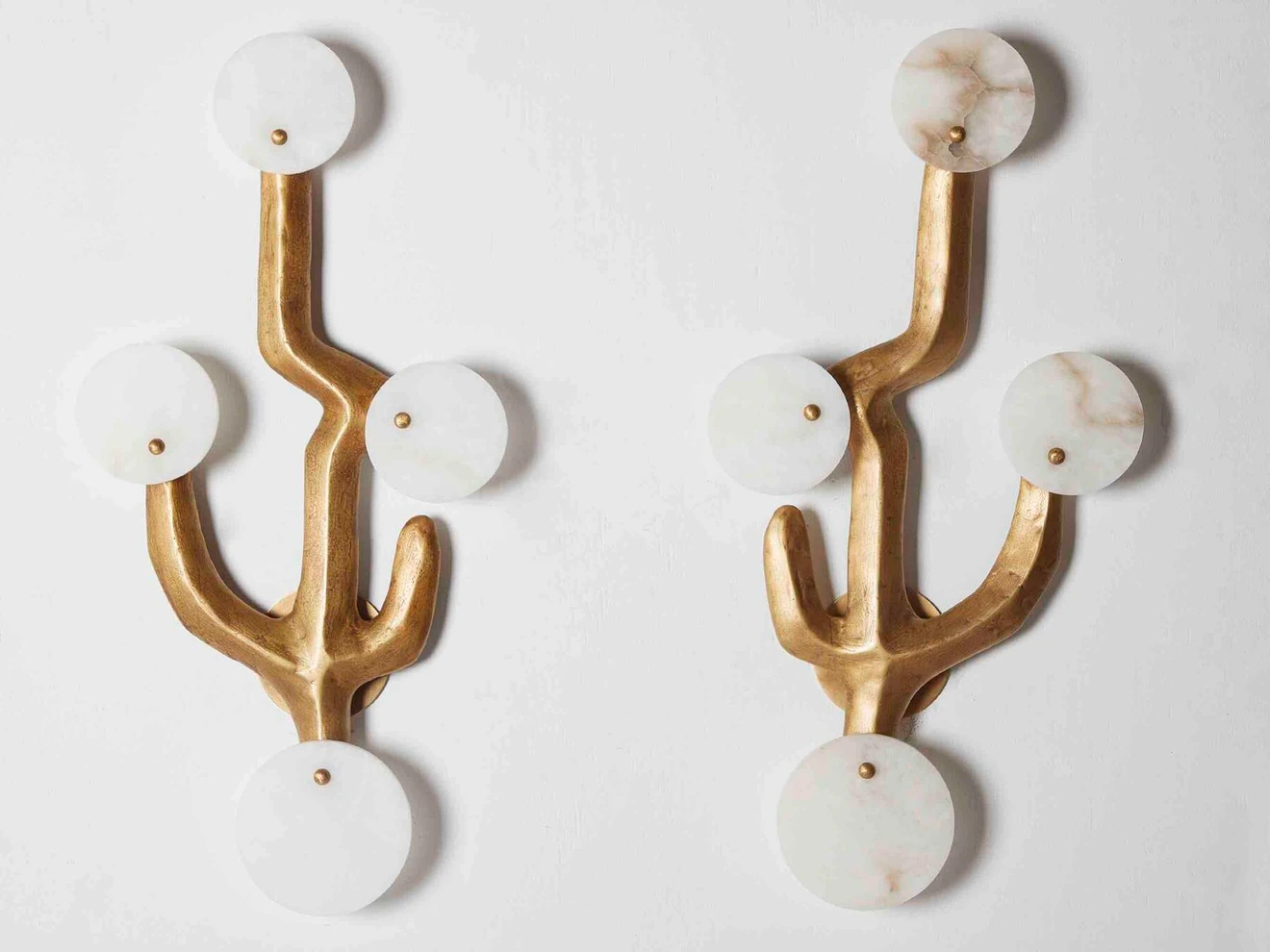 Pair of gold and white circular wall sconces with a branching, abstract design.