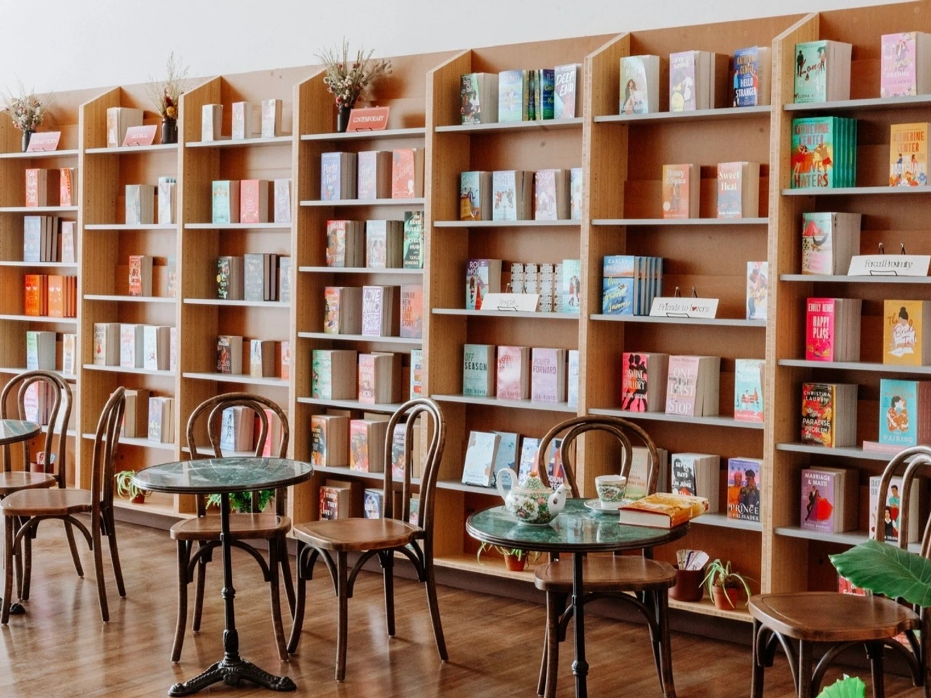 Cozy bookstore café with wooden bookshelves filled with books and round tables with chairs for customers.
