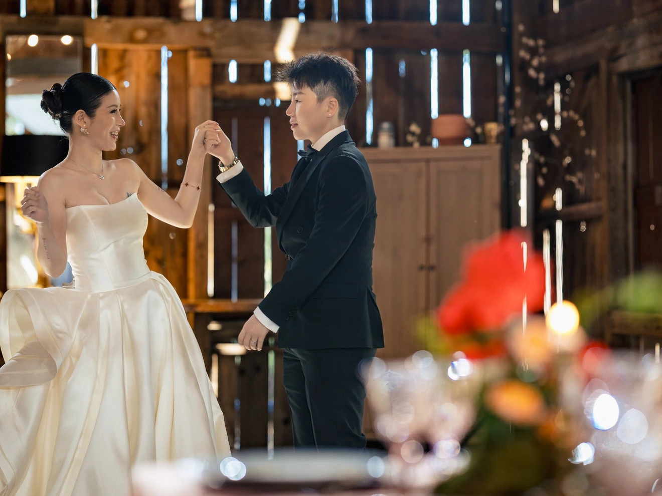 Bride and groom dancing in a warmly lit rustic venue during their wedding celebration.
