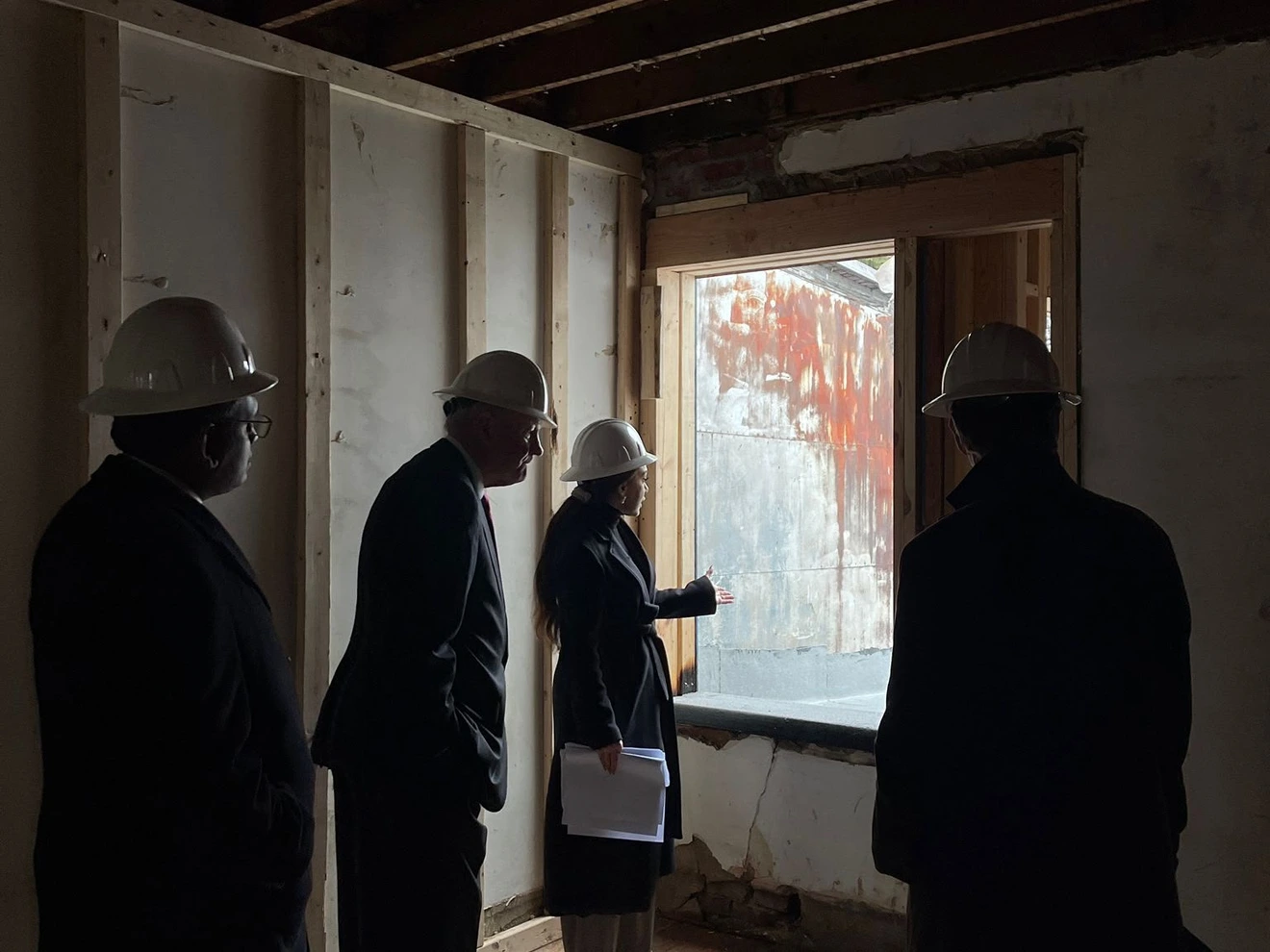 Four people wearing hard hats inspecting the interior of a building under construction.