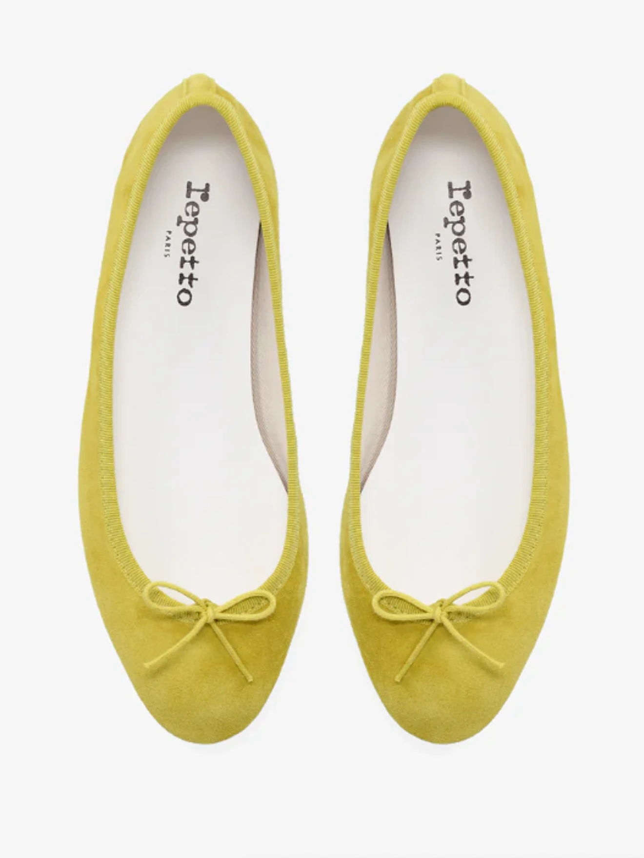 Pair of yellow Repetto ballet flats with small bows, viewed from above on a white background.