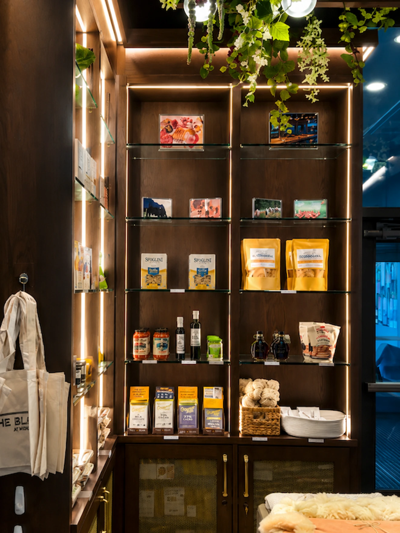 Interior of a cozy store display with shelves holding packaged goods, jars, and decorative plants above.