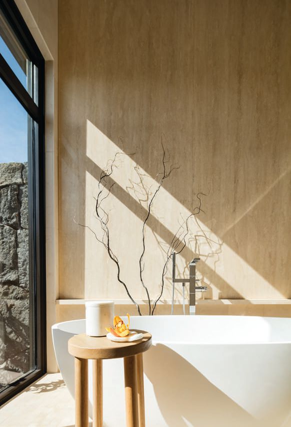 Oversized polished travertine slabs in the primary bath make a statement Photographed by Ethan Tweedie