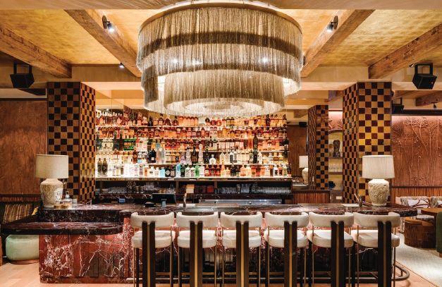 The bar at MILA Lounge is centered by a grand chandelier, serving as the focal point of the space. PHOTO BY ALEX TARAJANO PHOTOGRAPHY