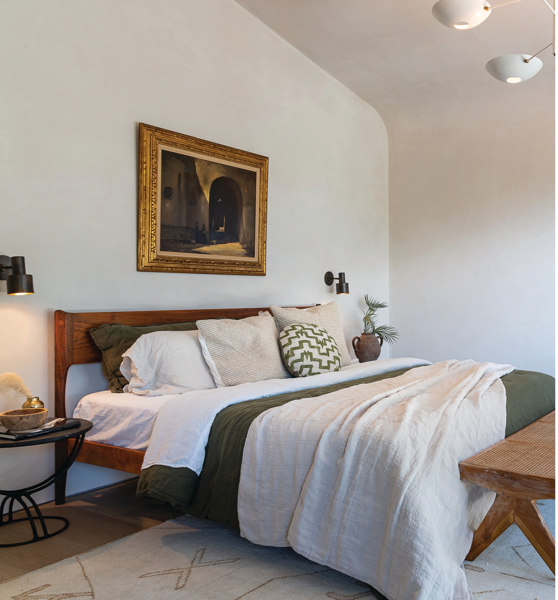 The primary bedroom is elevated and peaceful with rich touches throughout, such as the vintage gilded art piece above the bed. Bedding is from Evenfall Home and the rug is from Lulu and Georgia. PHOTOGRAPHED BY TODD GOODMAN