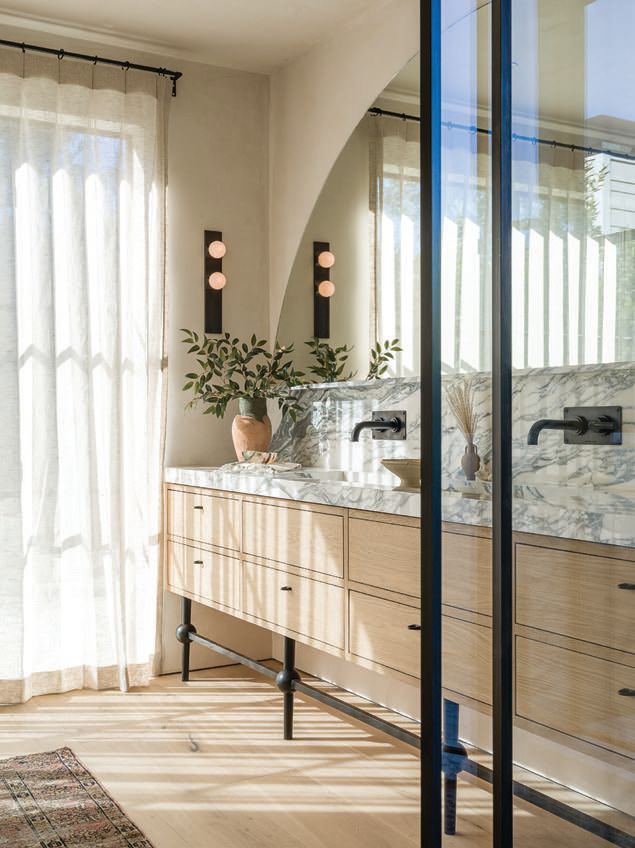 The primary bathroom’s custom sinks, mirrors and cabinetry mix with vintage hardware and rugs. PHOTOGRAPHED BY TODD GOODMAN