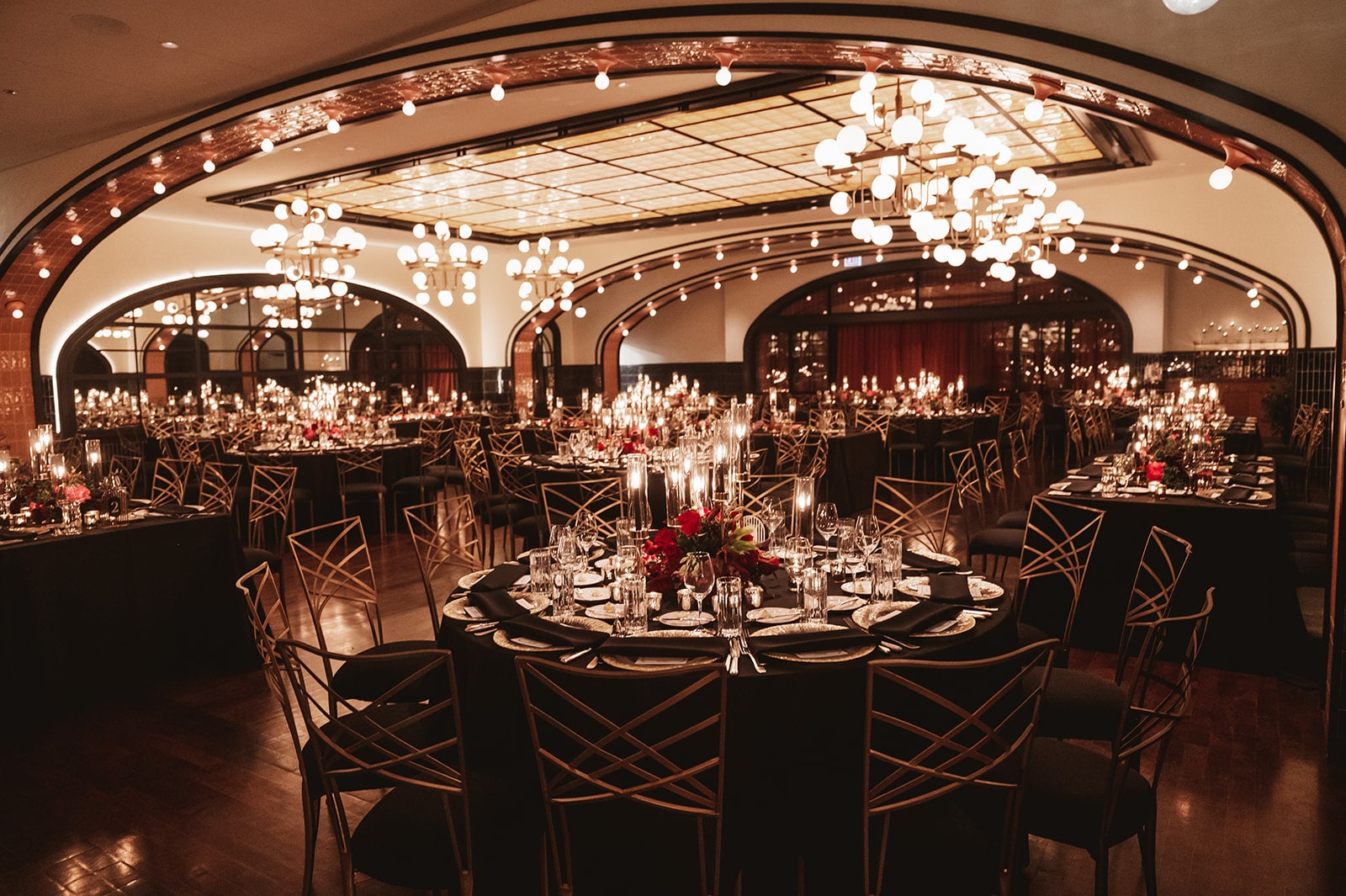 Elegant dining room setup with multiple tables, candles, and ambient lighting, creating a luxurious atmosphere.