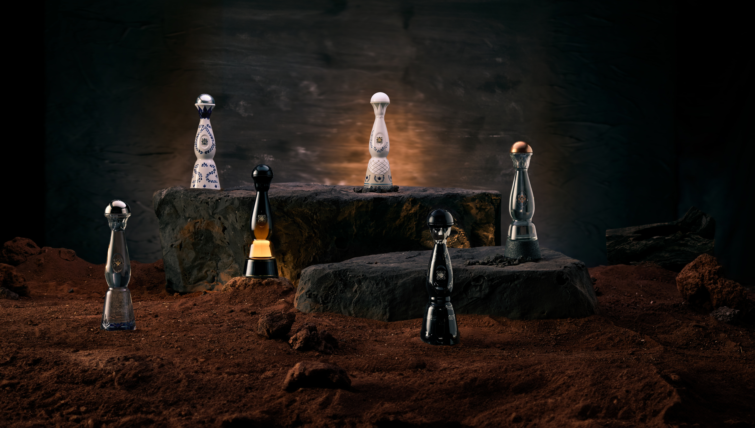 A collection of decorative bottles displayed on rocks, set against a dark background.