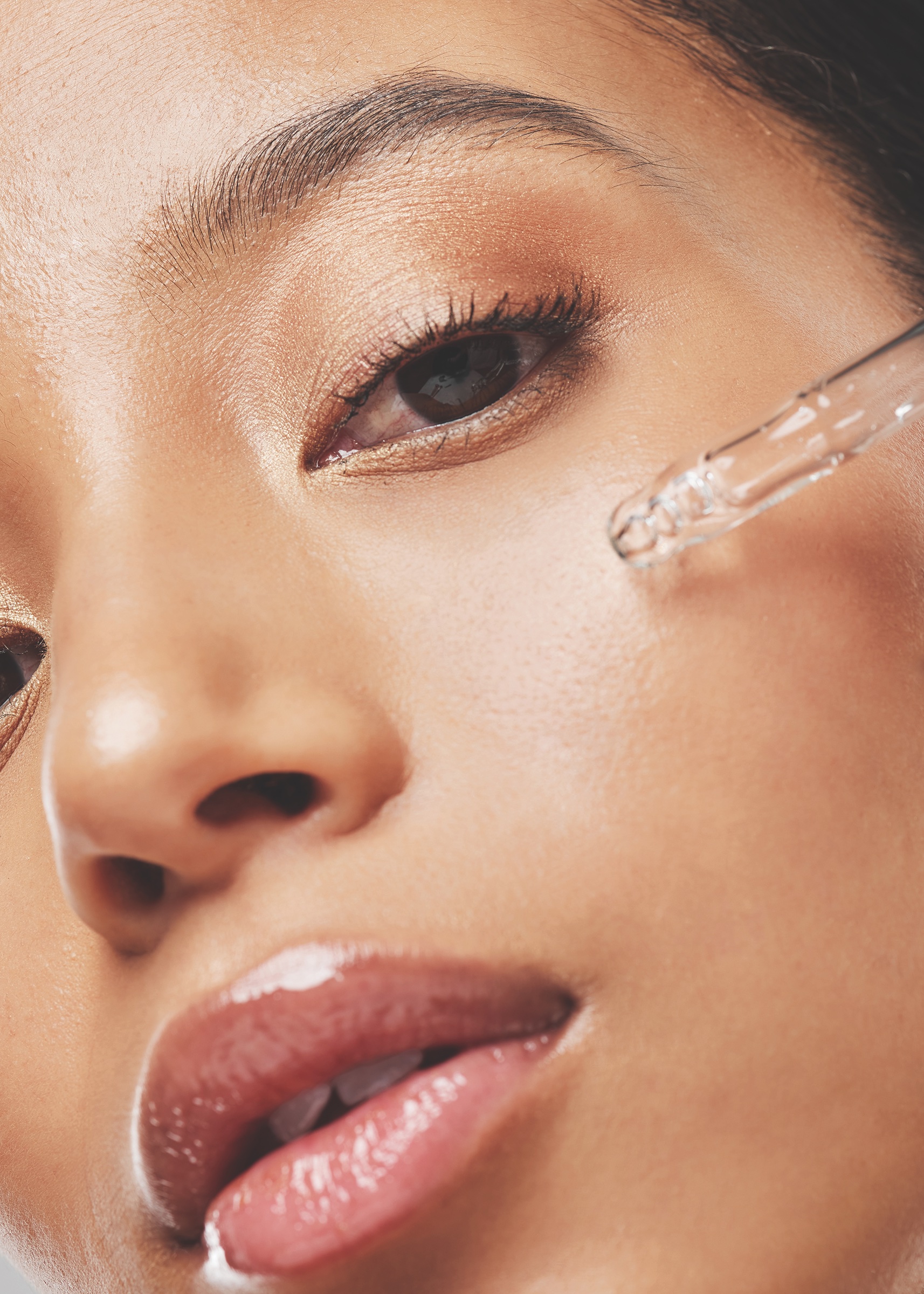 Portrait of an attractive young woman applying serum to her face