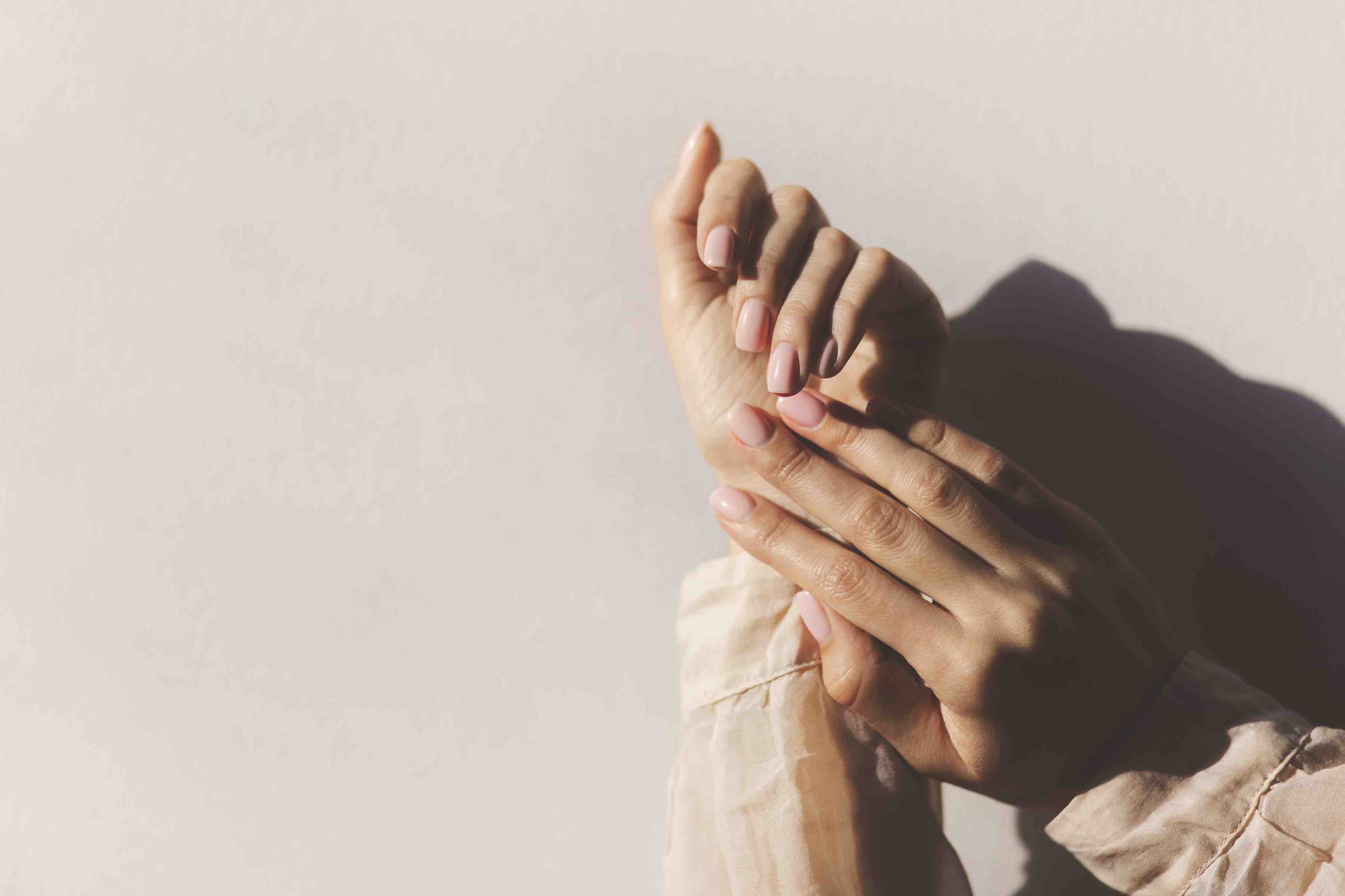 Manicure on female hands with light pink nail polish.