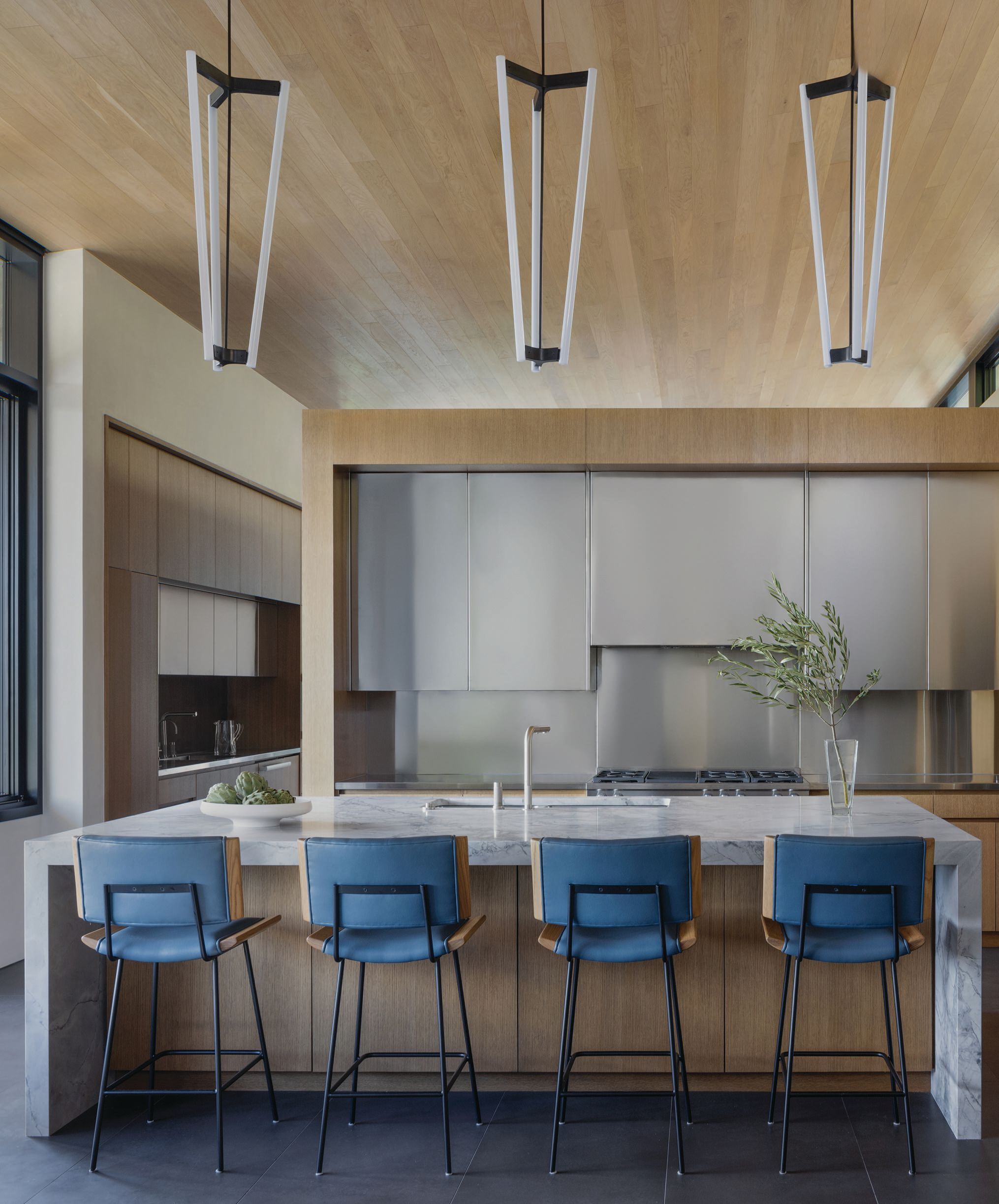 The kitchen features natural wood and stainless steel, as well as an overarching neutral palette that skews to grays, cream and a gray blue. photographed by ERIC PETSCHEK