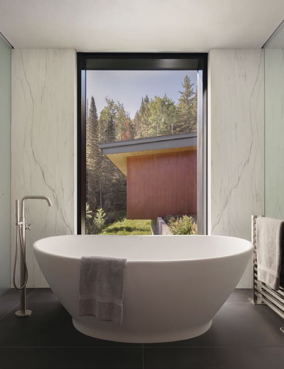 A soaking tub with exceptional views anchors the primary suite bath photographed by ERIC PETSCHEK