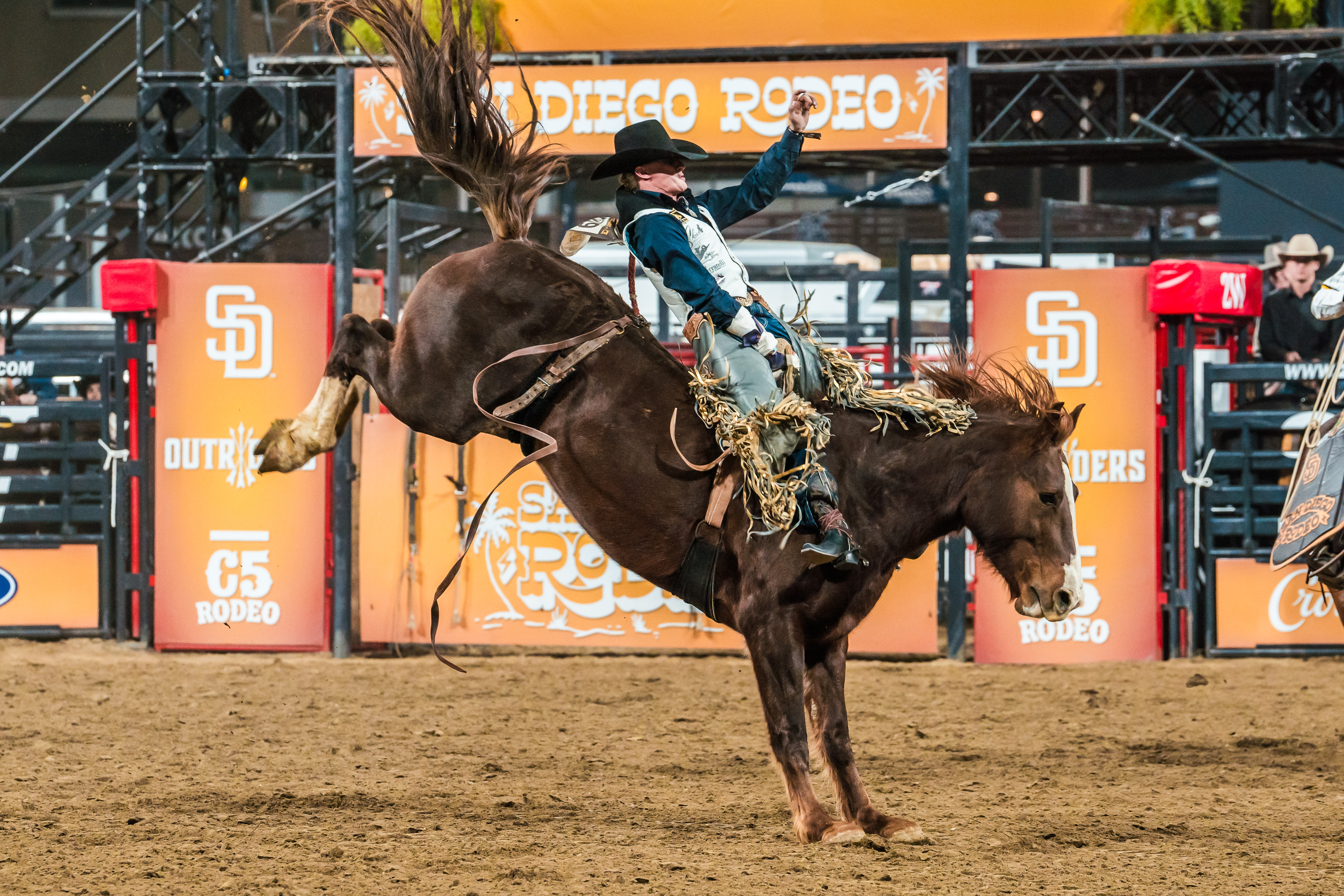 Rodeo cowboy riding a bucking horse at the San Diego Rodeo event.