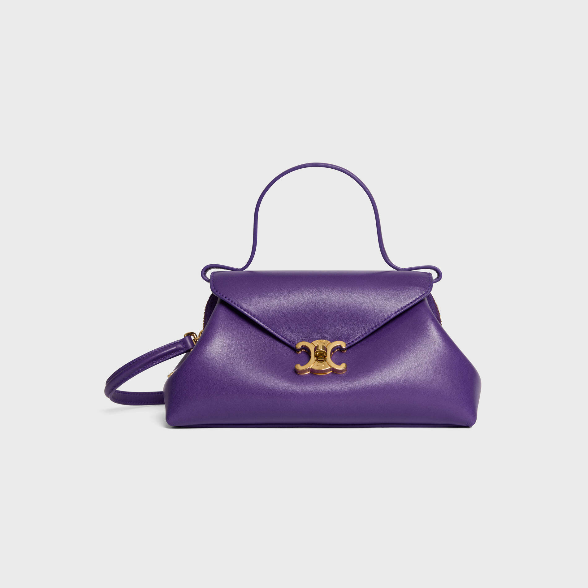 Purple leather handbag with gold clasp and short handle on a plain background.